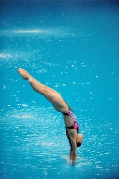 a woman diving into the water with her hands up in the air while wearing a pink and purple swimsuit