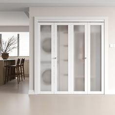 an empty room with white walls and glass doors on the door, in front of a dining table