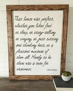 a wooden frame with a poem written in cursive writing next to a potted plant