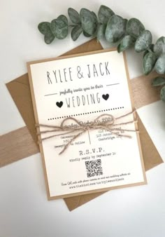 an image of wedding stationery with greenery on the side and brown paper tied to it