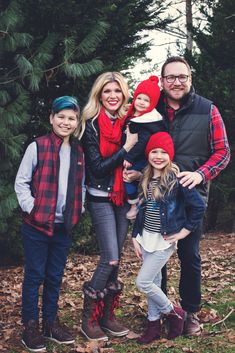 a family poses for a photo in front of some trees with leaves on the ground