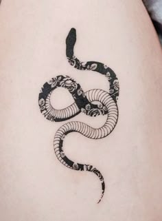 a black and white snake tattoo on the back of a woman's thigh,