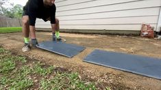 a man is doing push ups in front of a house with grass and dirt on the ground