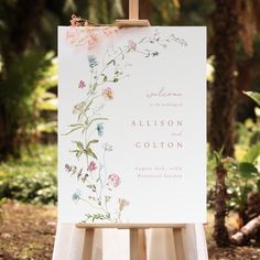 an easel with a wedding sign on it in front of some trees and bushes