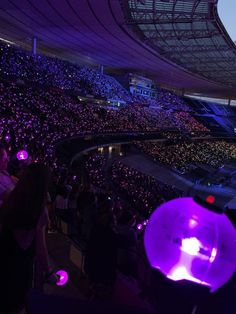 a large stadium filled with lots of purple lights and people sitting in the bleachers