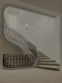 a white staircase with wrought iron railings in a large room, leading up to the second floor