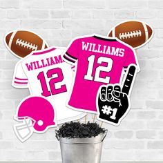 a football jersey cake topper and cupcake picks are in a bucket with dirt