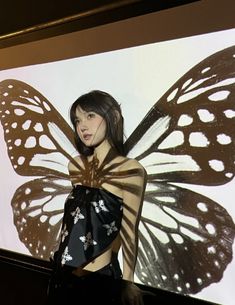 a woman is standing in front of a screen with a butterfly cut out on it