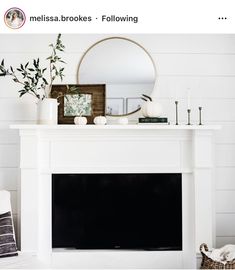 a living room with a fireplace, mirror and vases on top of the mantel