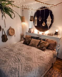 a bed with pillows and blankets in a room that has lights strung from the ceiling