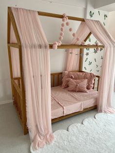 a pink canopy bed with curtains and pillows on the bottom bunk, in a girls'bedroom