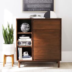 a wooden cabinet sitting next to a potted plant