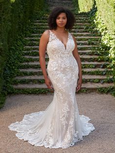 a woman standing in front of some stairs wearing a wedding dress with an open back