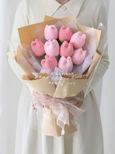 a woman holding a bouquet of pink crocheted hearts