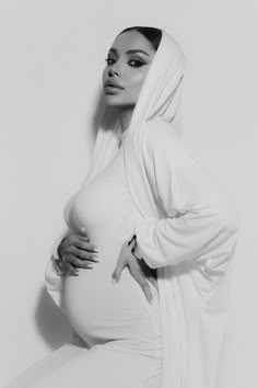 a pregnant woman poses for a black and white photo with her hands on her hips