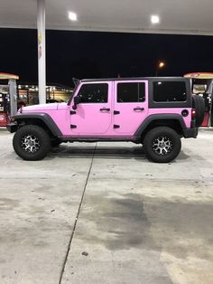 a pink jeep is parked at a gas station