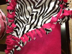 a zebra print blanket on top of a table next to a pink and white cake