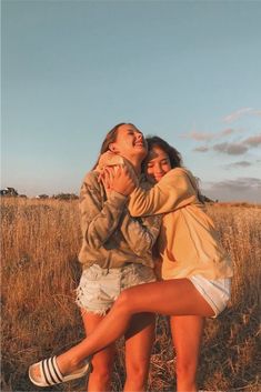 two young women are hugging in a field