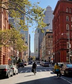 a person riding a bike down the middle of a street with tall buildings in the background