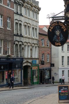 people are walking down the street in front of some old buildings and shops with signs on them