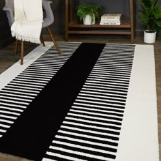 a black and white striped rug on the floor in a living room with a chair