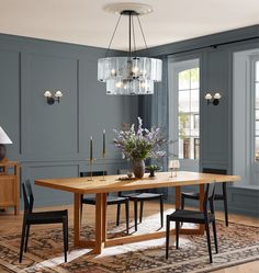 a dining room with blue walls and wooden table surrounded by chairs, chandelier and rug