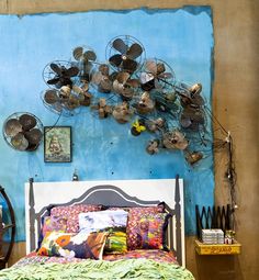 a bed sitting under a blue wall covered in lots of metal pots and pans