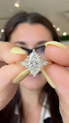 a woman holding up a diamond ring in front of her face