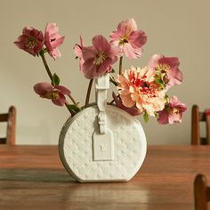 a white vase with pink flowers in it on a table