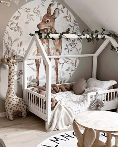 a child's room with a bed, table and giraffe mural on the wall