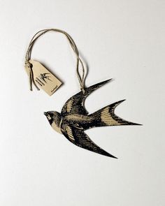 a small bird ornament hanging from a string with a tag attached to it