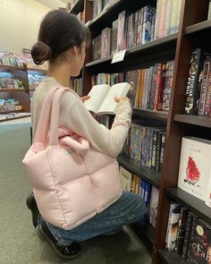 a woman sitting on a wheel chair in front of a book shelf holding an open book