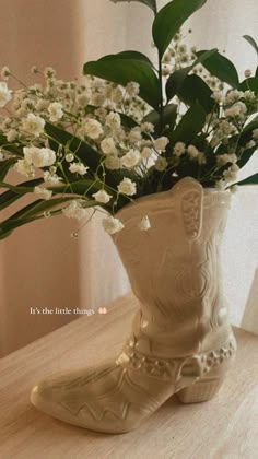 a white boot with flowers in it sitting on a table