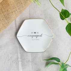 a white plate with the word engaged on it next to green leaves and burlock