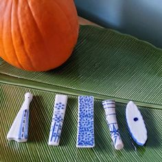 four pieces of blue and white pottery sit on a green tray next to a pumpkin