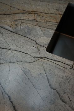 a cell phone sitting on top of a marble counter next to a black object in the middle