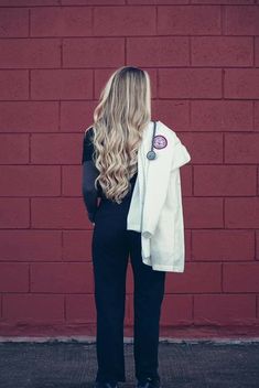 a woman standing in front of a red brick wall with her back to the camera