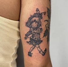 a woman's arm with a small tattoo of a girl in a dress on it