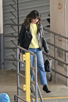 a woman in black jacket and jeans walking down stairs