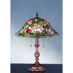 a stained glass lamp sitting on top of a wooden table next to a blue wall