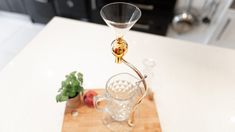 a wine glass on a cutting board next to a knife and pepper shaker in a kitchen