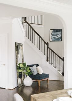 a living room with a blue chair and mirror on the wall next to a stair case