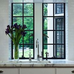 a kitchen with an open window that has flowers in it and a vase on the counter