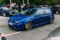 a blue car parked in a parking lot next to other cars