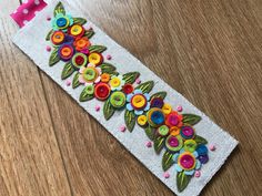 a white bracelet with colorful flowers on it sitting on top of a wooden table next to a pair of scissors