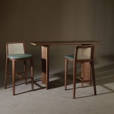 two chairs and a table with one chair at the end, in front of a wall