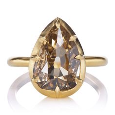 a pear shaped brown diamond in a yellow gold ring