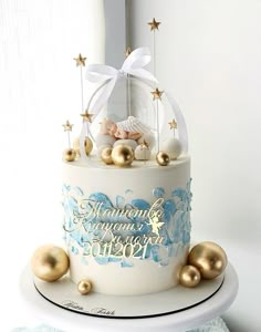 a white and blue cake with gold ornaments on it's side, sitting on a table