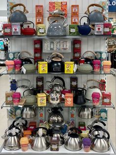 a display case filled with tea pots and kettles on top of shelves in a store