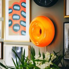 an orange object sitting on top of a table next to pictures and flowers in front of a clock